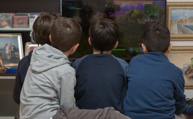 En gjeng med gutter samlet foran en skjerm mens de spiller